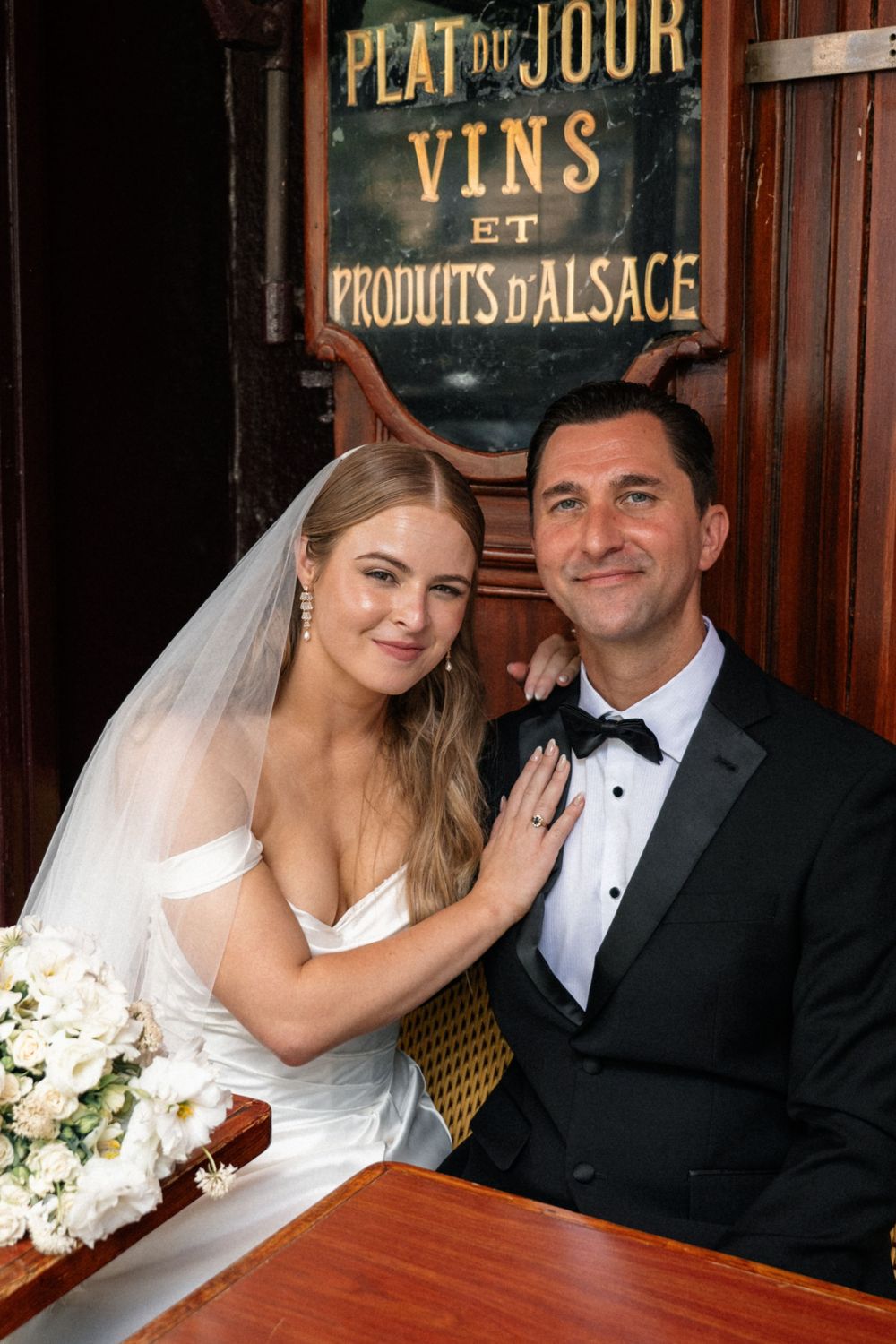Wedding couple in front of vintage French cafe signage and decor.