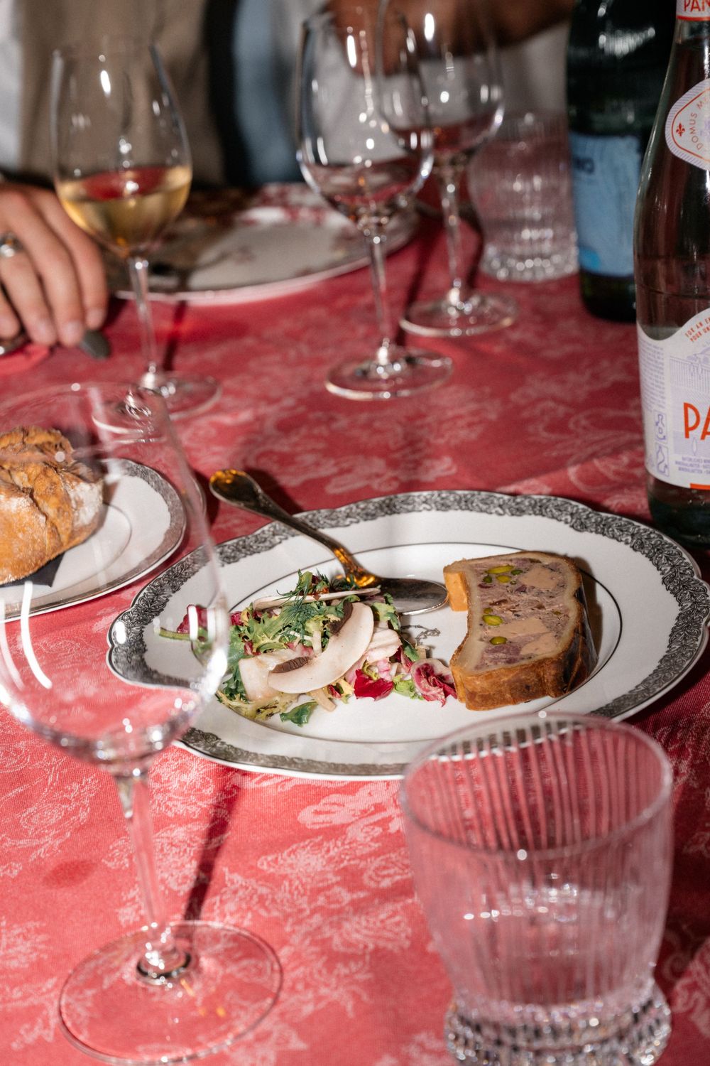Elegant dinner table setting with plated meals and wine glasses on a red tablecloth.