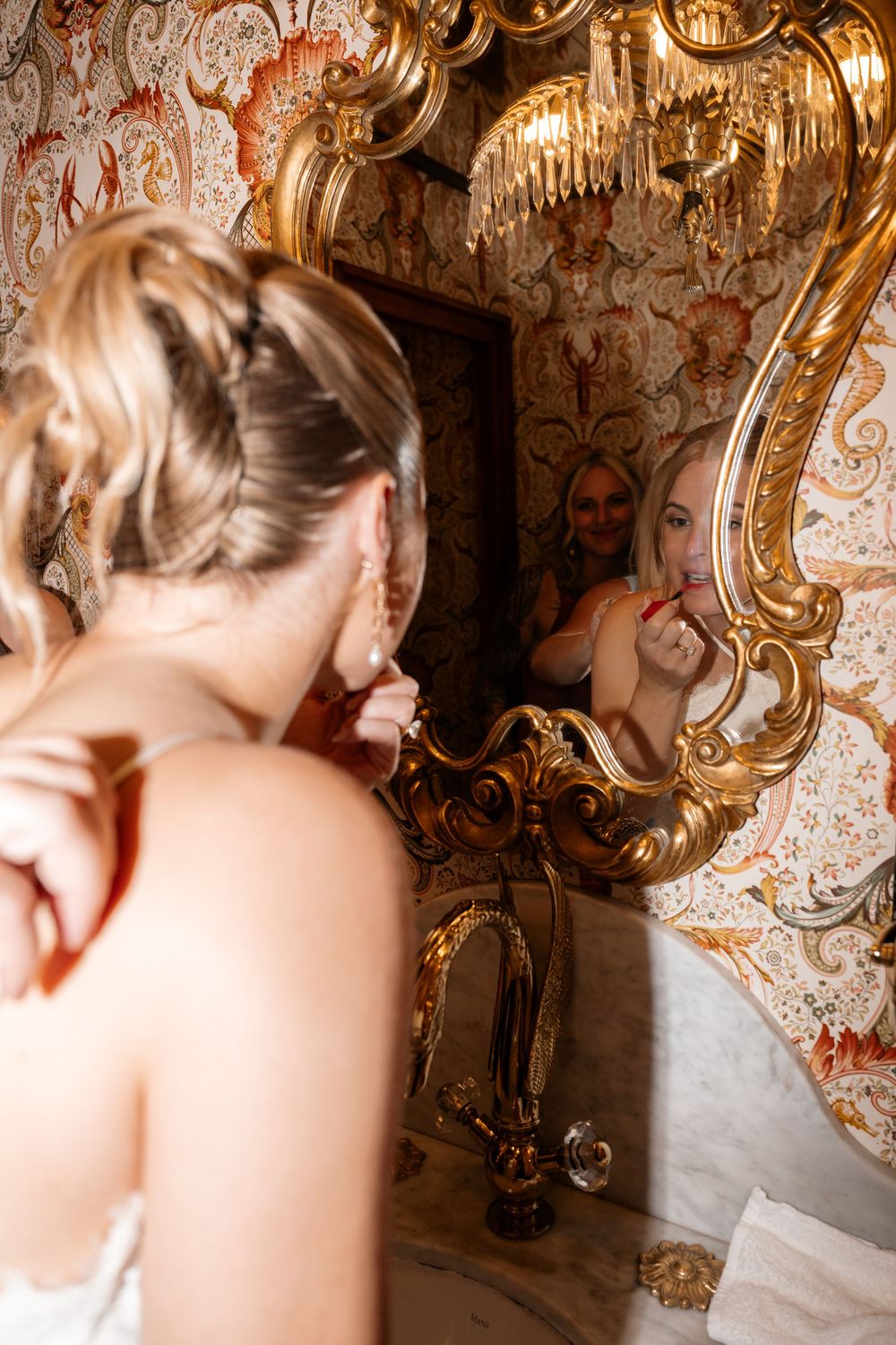 Close-up portrait featuring blonde hair and ornate gold baroque mirrors in a vintage-styled interior.