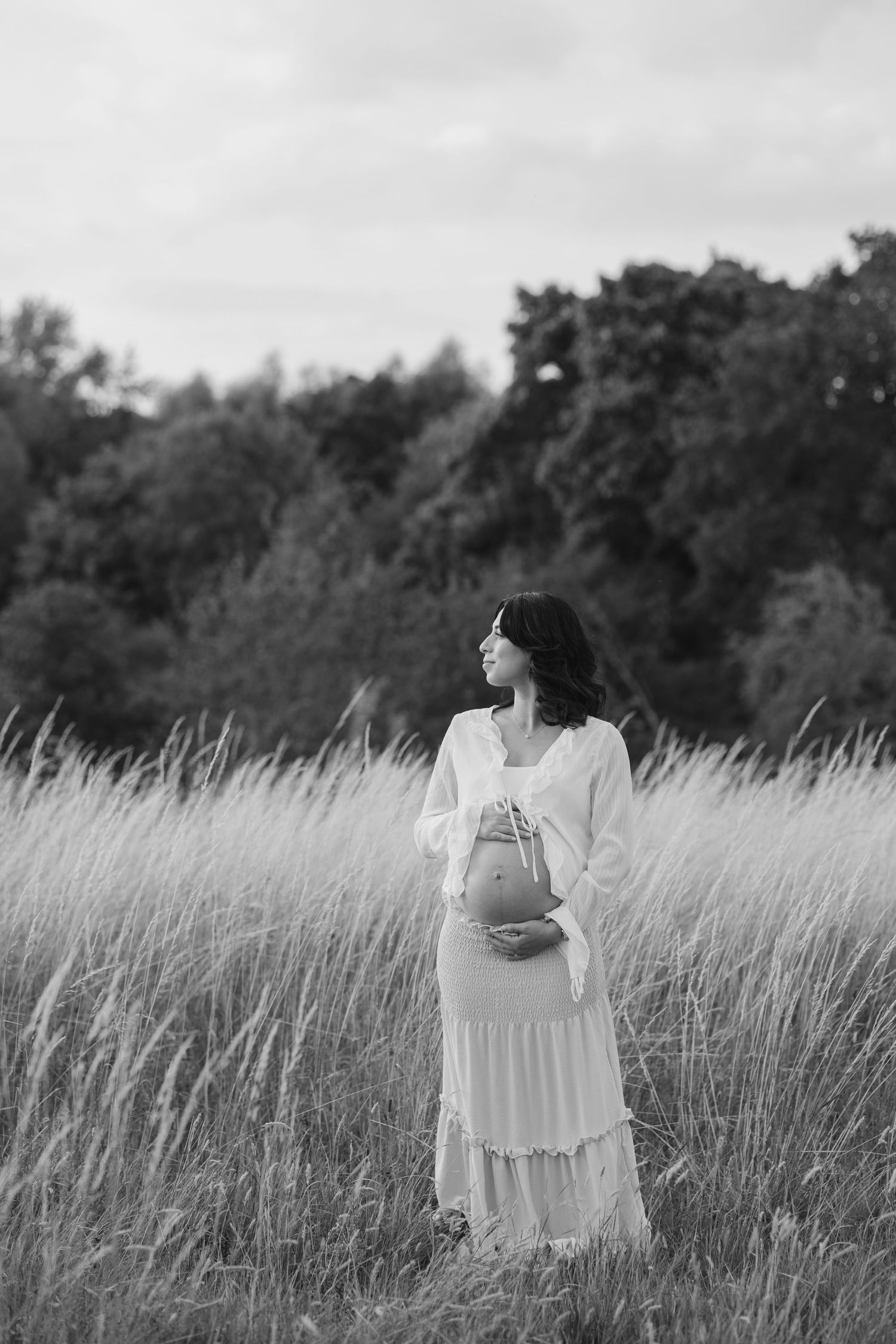 A series of ethereal black and white photos showing a figure in a white dress standing in a tall grass field.