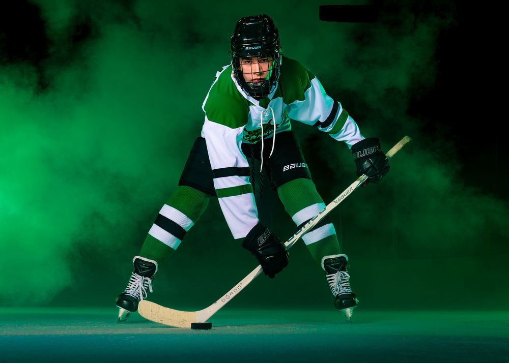 Hockey player in Keystone Kraken uniform skating forward through green fog during Media Day at Twin Ponds East.