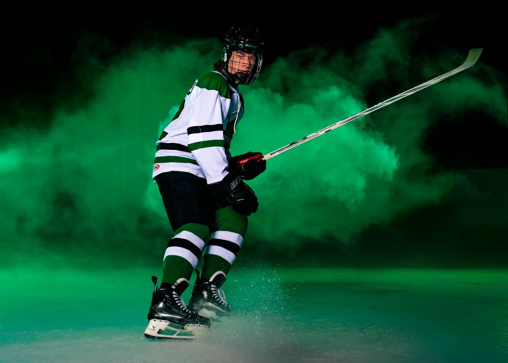 Hockey player in Keystone Kraken uniform skating forward through green fog during Media Day at Twin Ponds East.