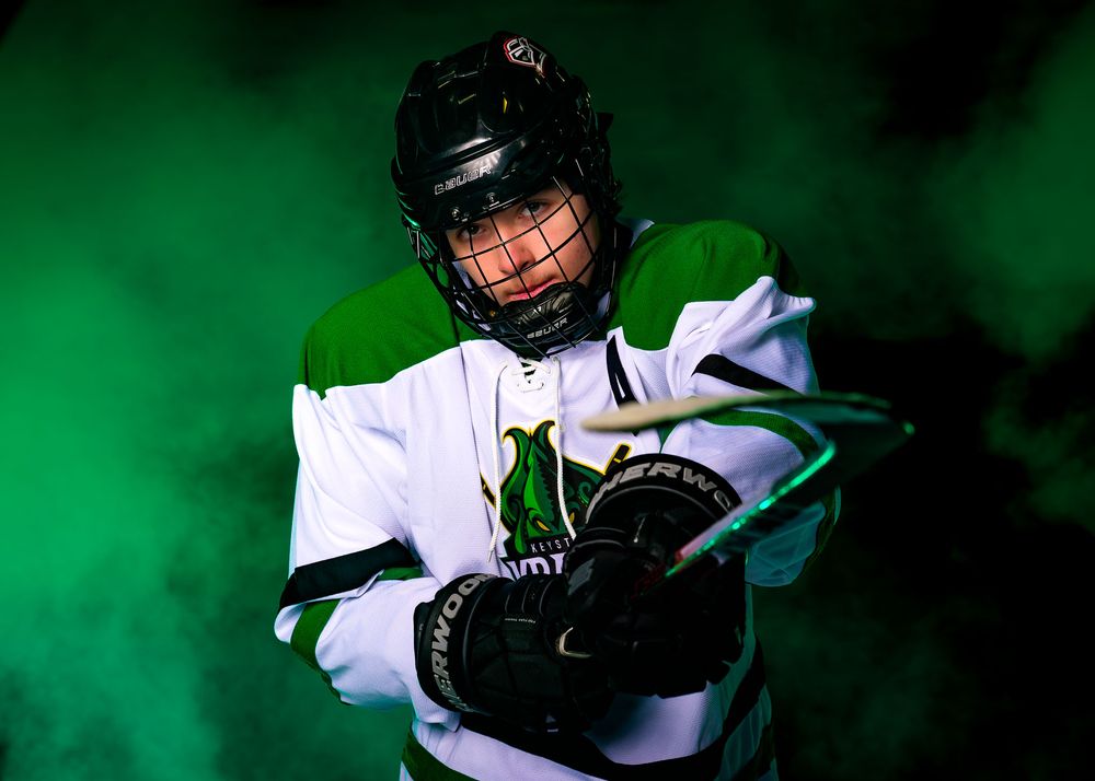 Close-up portrait of a Keystone Kraken hockey player in helmet and uniform, set against a green foggy background.