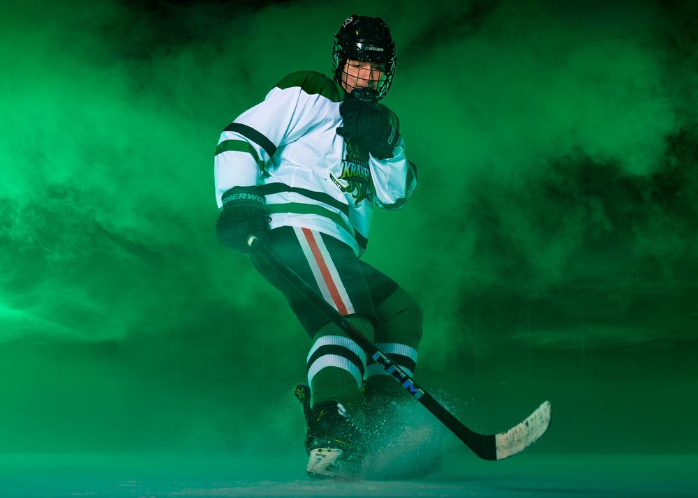 Hockey player in Keystone Kraken uniform skating forward through green fog during Media Day at Twin Ponds East.