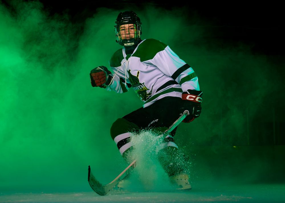 Hockey player in Keystone Kraken uniform skating forward through green fog during Media Day at Twin Ponds East.