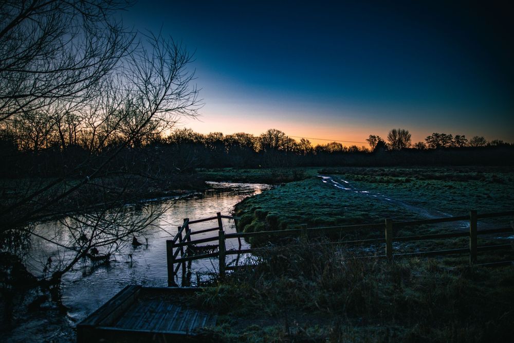 A series of scenic sunset landscapes with silhouetted trees and wooden fences against a darkening blue sky.