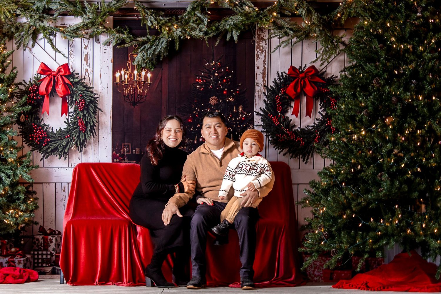 A festive holiday photo session with red and white decor, Christmas trees, and a cozy indoor setting.