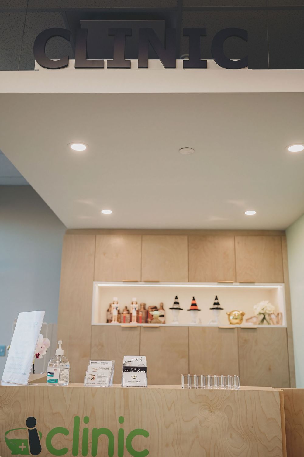 Modern medical clinic interior with minimalist reception desk and illuminated signage on neutral-toned walls.