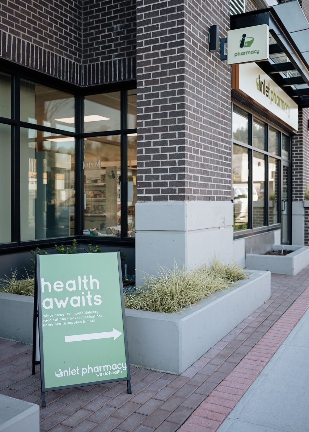 Exterior view of a brick building with pharmacy signage and valet pharmacy service featuring modern landscaping.