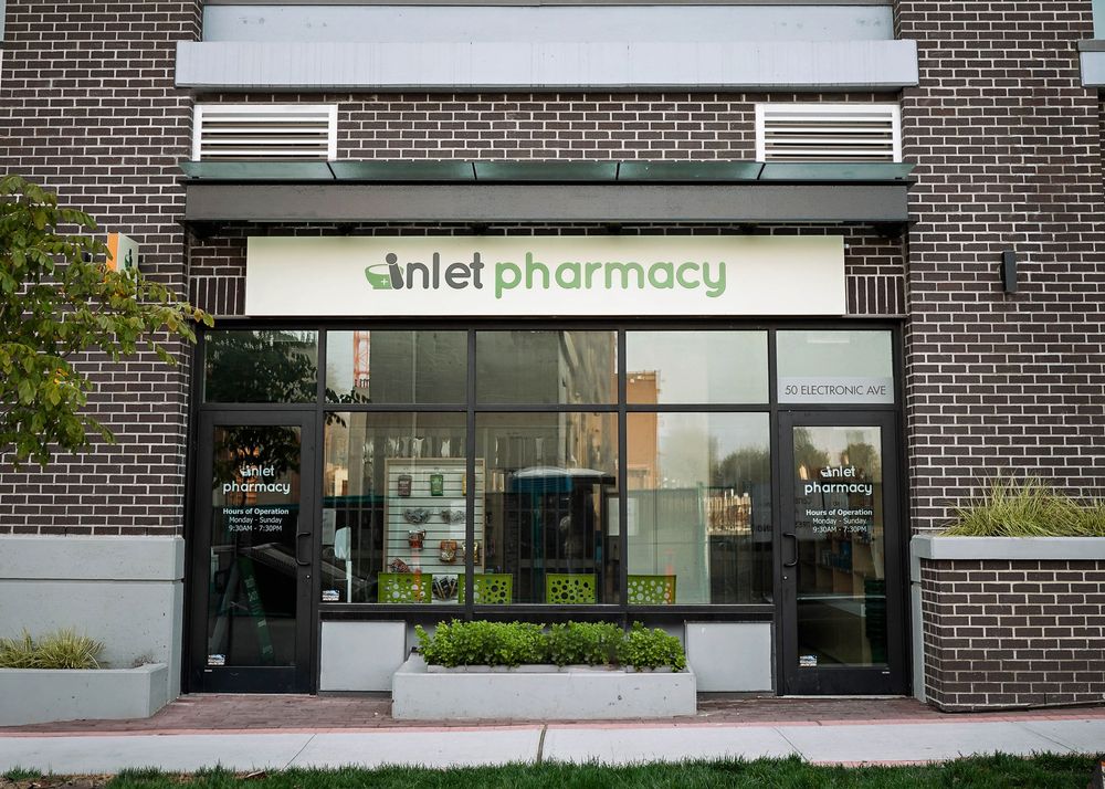 A storefront of an Inlet pharmacy with dark brick exterior and modern signage displayed on the building facade.