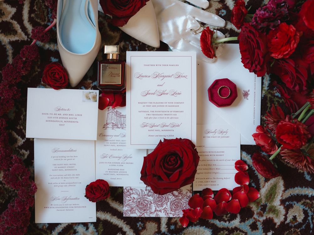 Wedding invitation suite displayed with deep red roses and elegant calligraphy on white stationery.