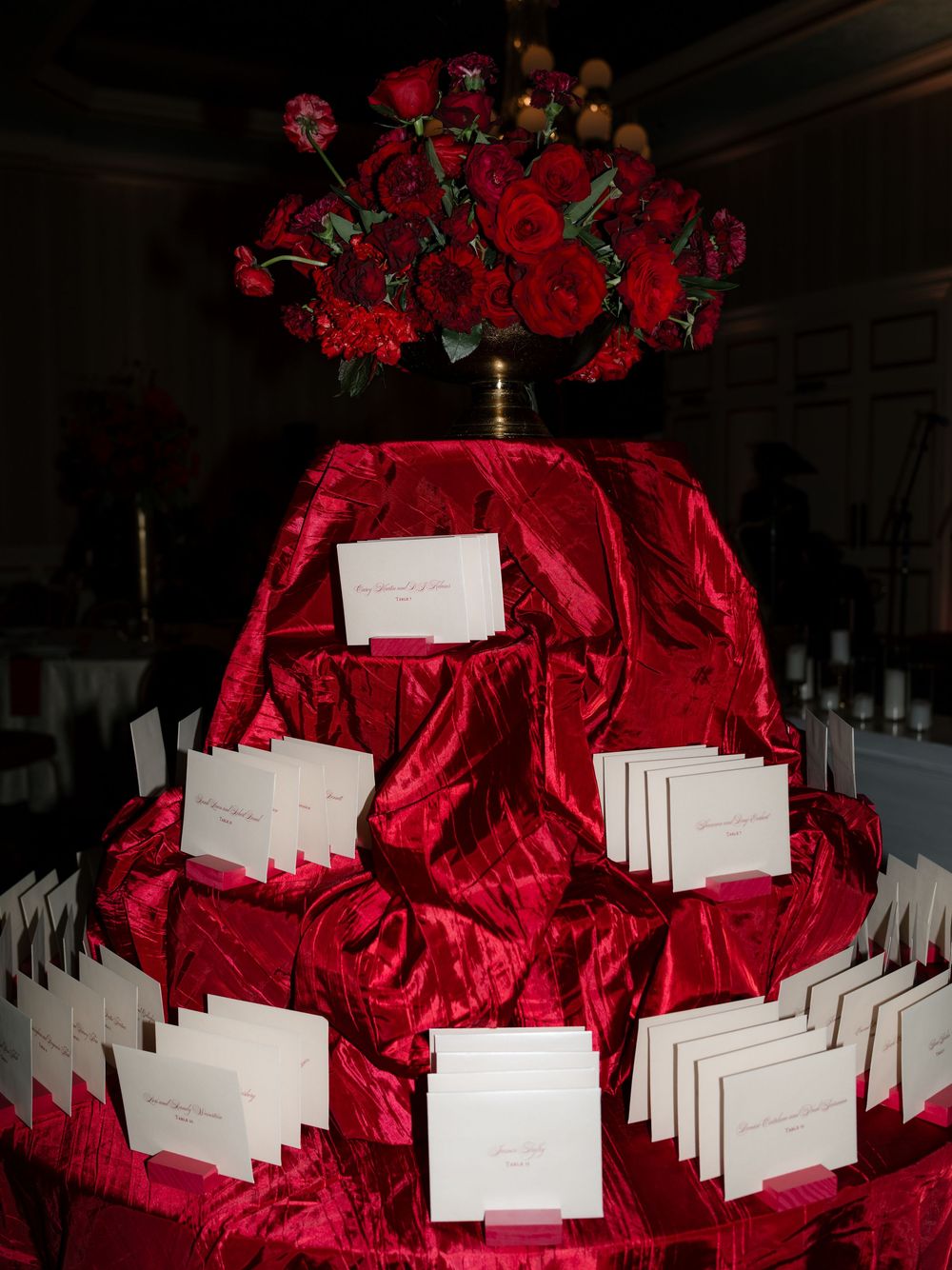 Red floral centerpiece with white place cards arranged in a circular pattern for an elegant event seating display.
