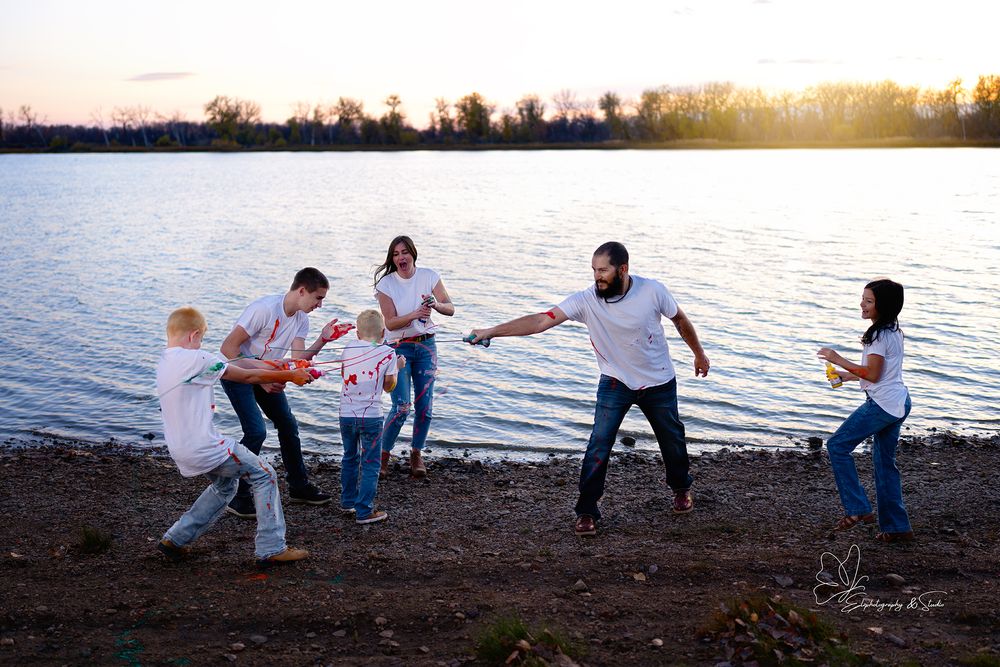 A group plays tug of war on a lakeside beach at sunset with golden light reflecting off the water in Williston, North Dakota.