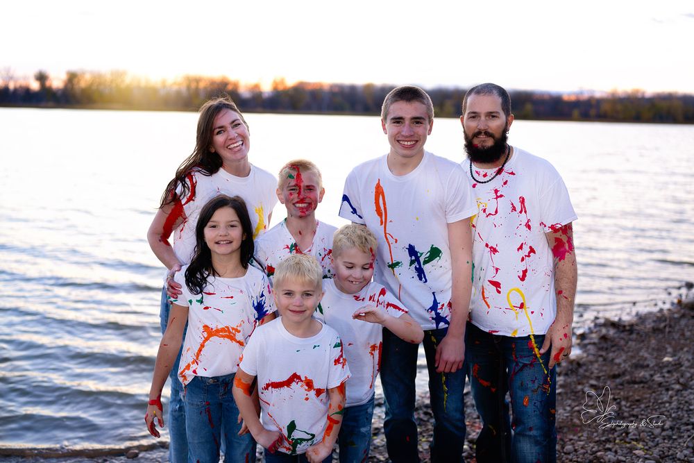 Family wearing white shirts with orange paint splatter at sunset by the water in Williston, North Dakota.