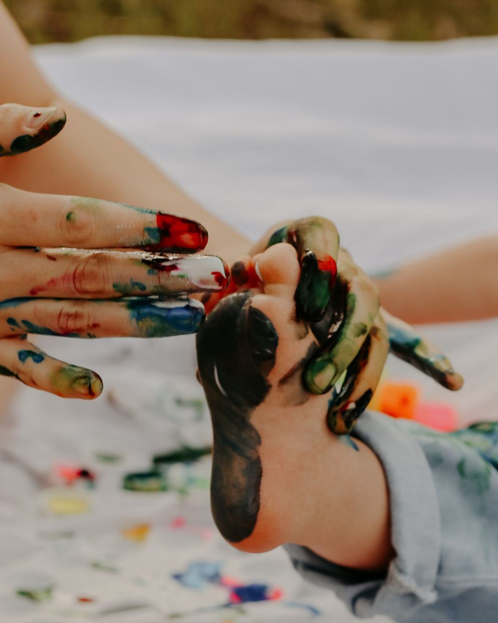Close-up shots of hands finger painting with colorful paints on a light surface in Williston, North Dakota.