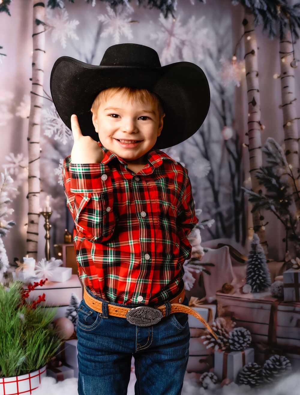 Holiday photoshoot with plaid shirt and cowboy hat in a winter woodland setting in Williston, North Dakota.