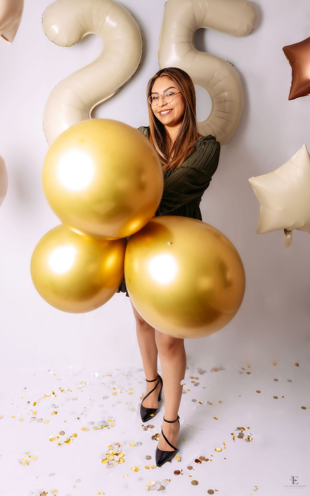 Celebratory photo session with large gold balloons against white background in Williston, North Dakota.