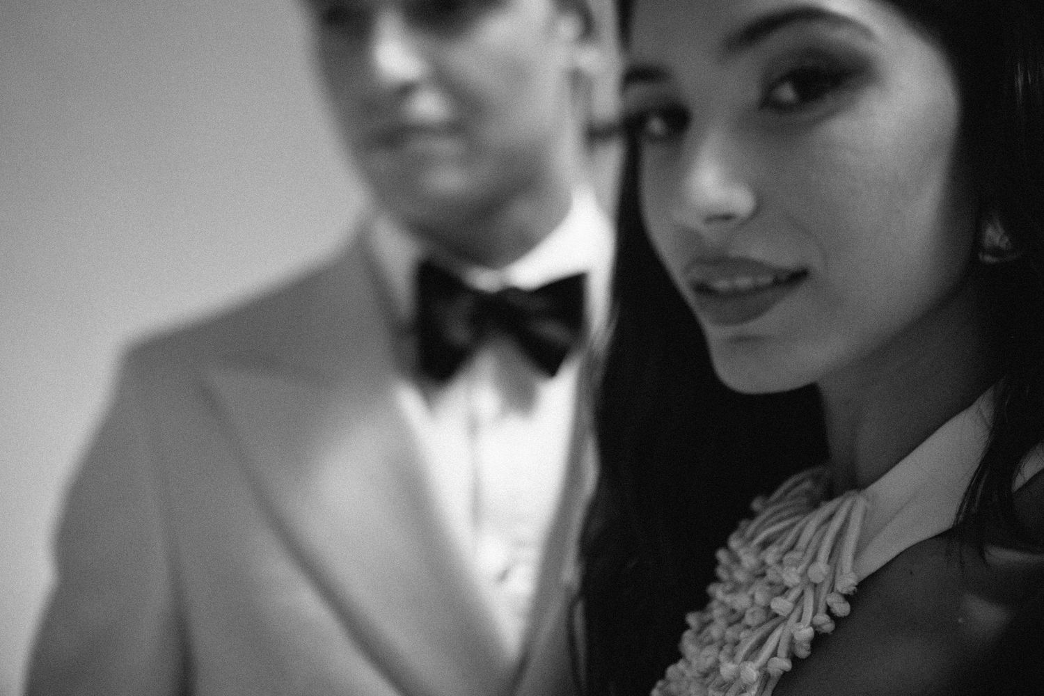Intimate black and white close-up of a couple in formal wedding attire.