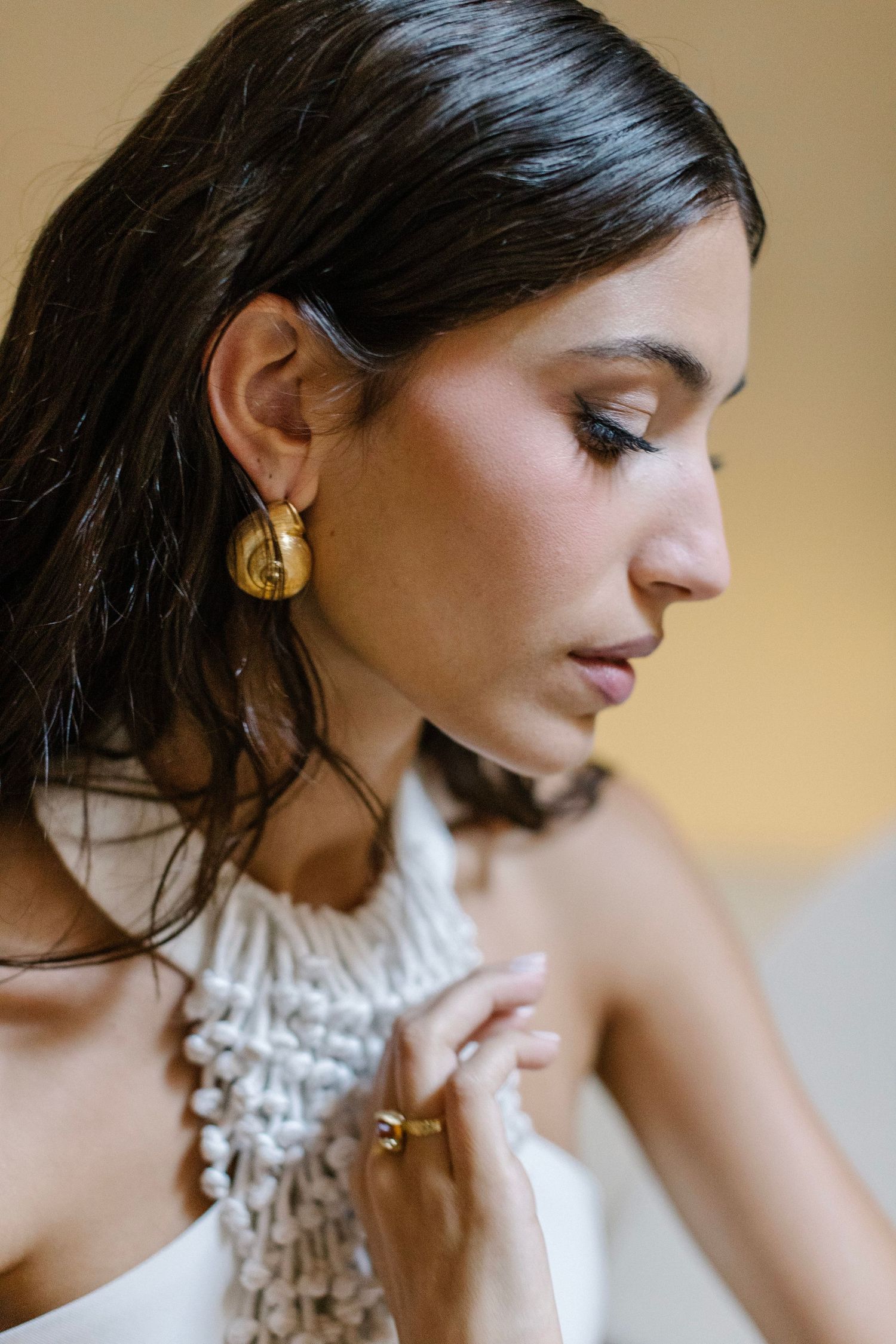 A series of artistic profile shots showing a person wearing a white ruffled top and delicate gold earrings.