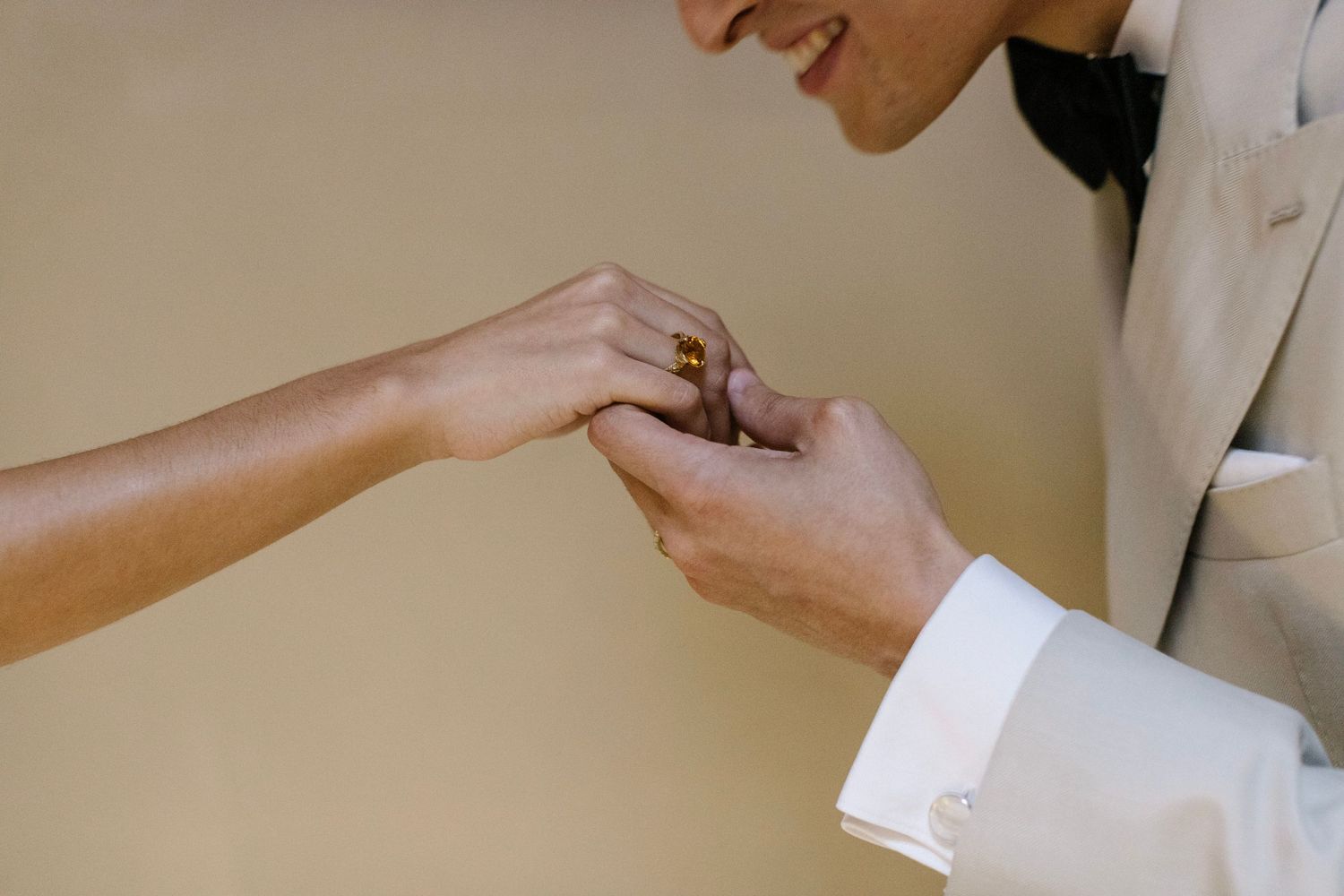 Hands reaching out to adjust clothing details in a minimalist setting.