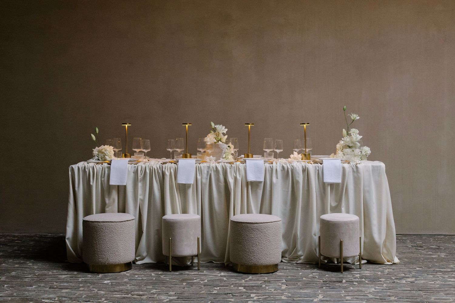 A row of white candles with floral arrangements on top arranged in a minimalist style against a neutral background.