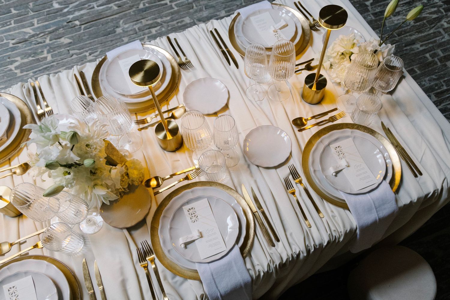 Luxurious wedding reception table with gold details and white floral centerpieces.