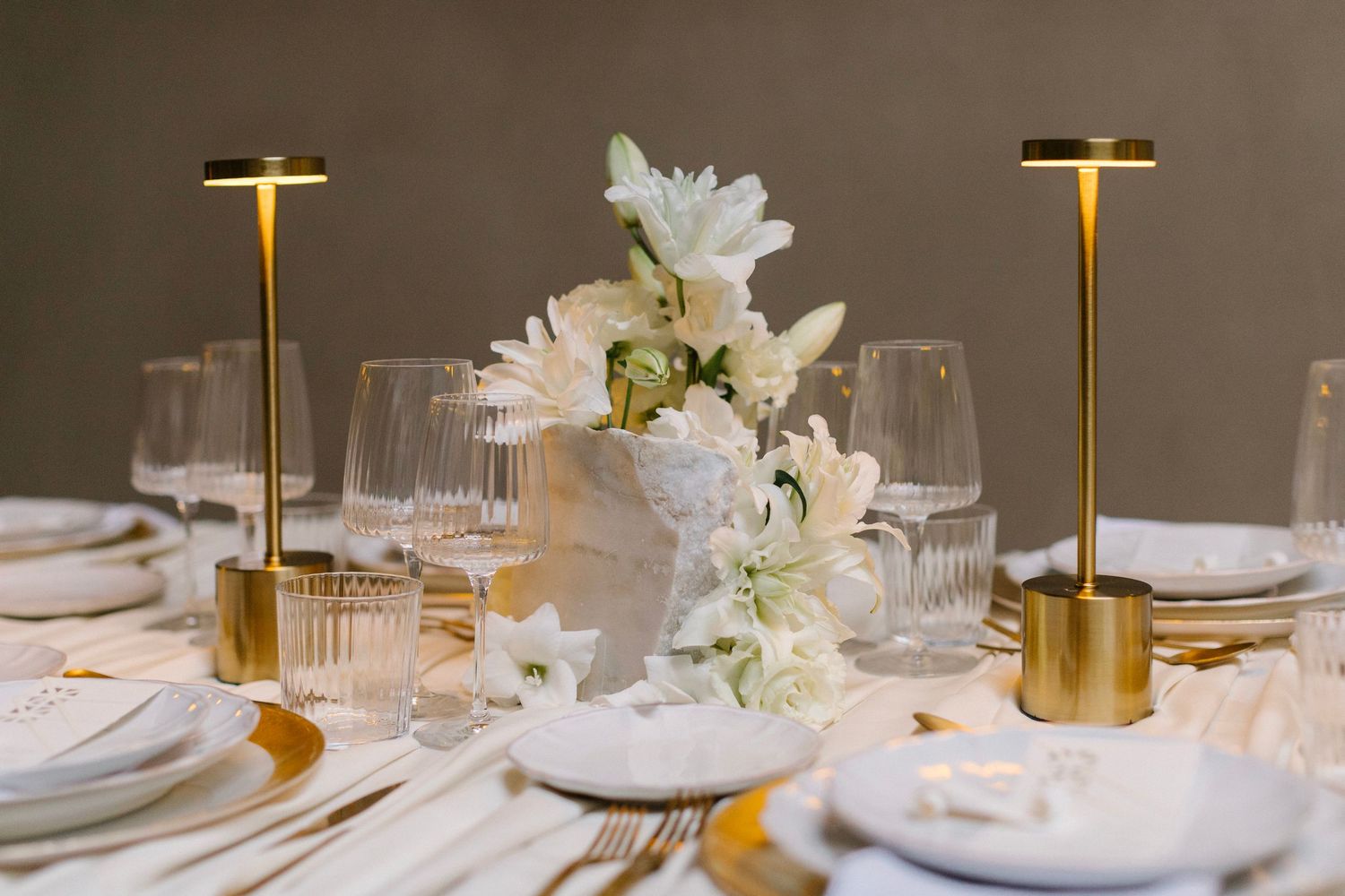 Elegant table setting with gold accents, white flowers and crystal glassware.