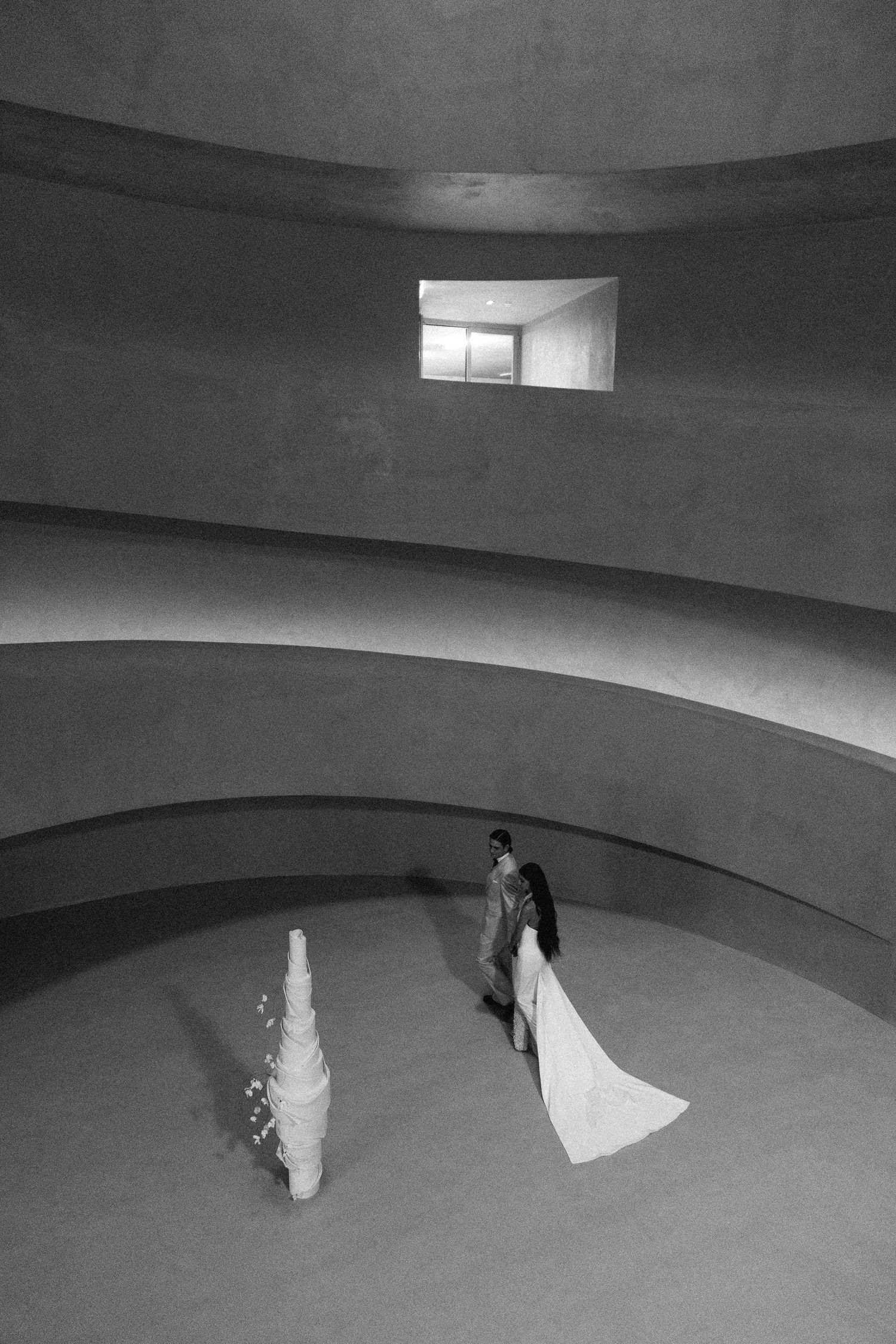 Dramatic black and white photos of a curved concrete space with architectural elements.
