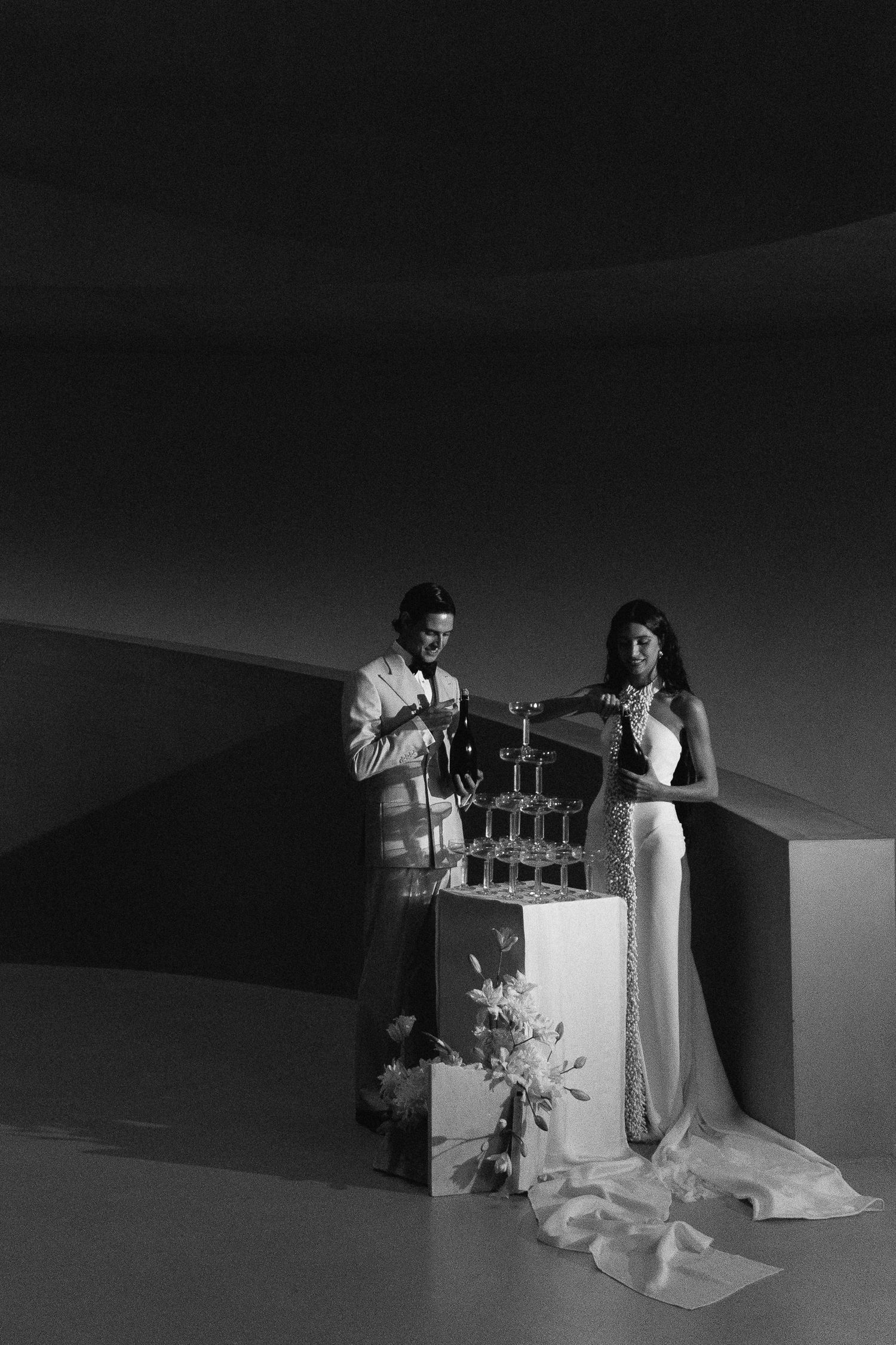 Moody black and white photos capturing intimate moments in a dark architectural space.