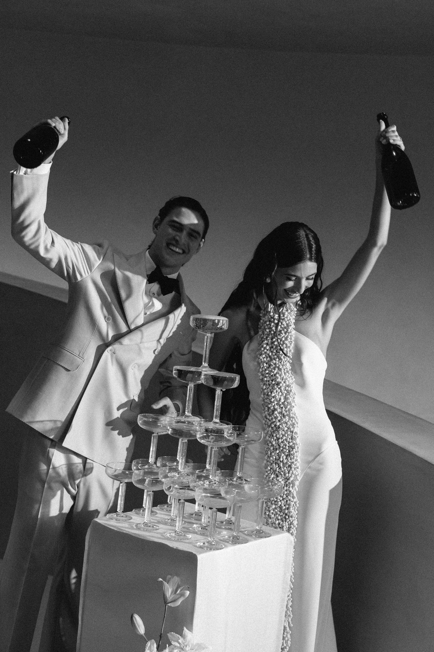 Black and white sequence of people celebrating with a champagne tower at an event.