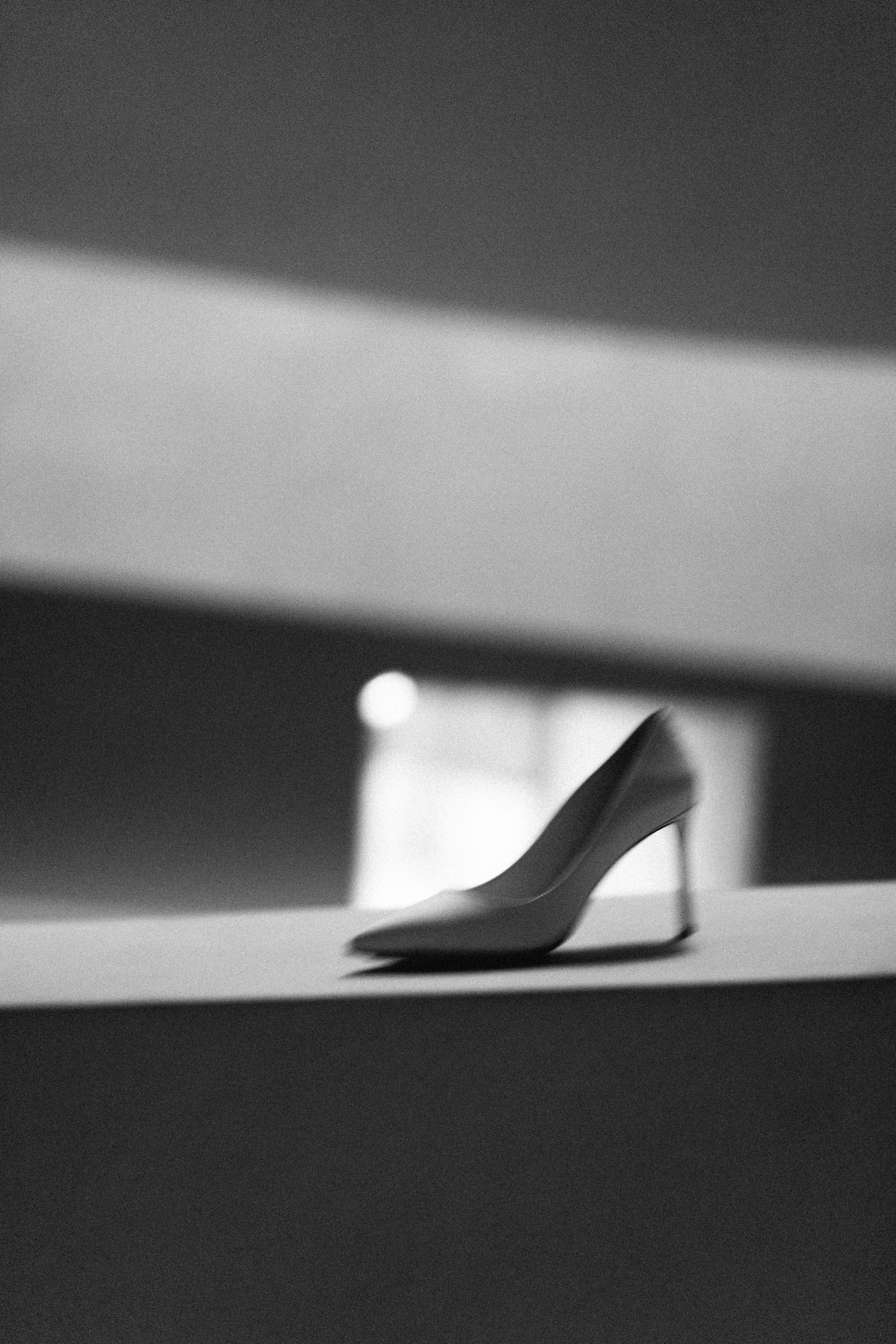 Minimalist black and white photograph of a high heel shoe casting a dramatic shadow.