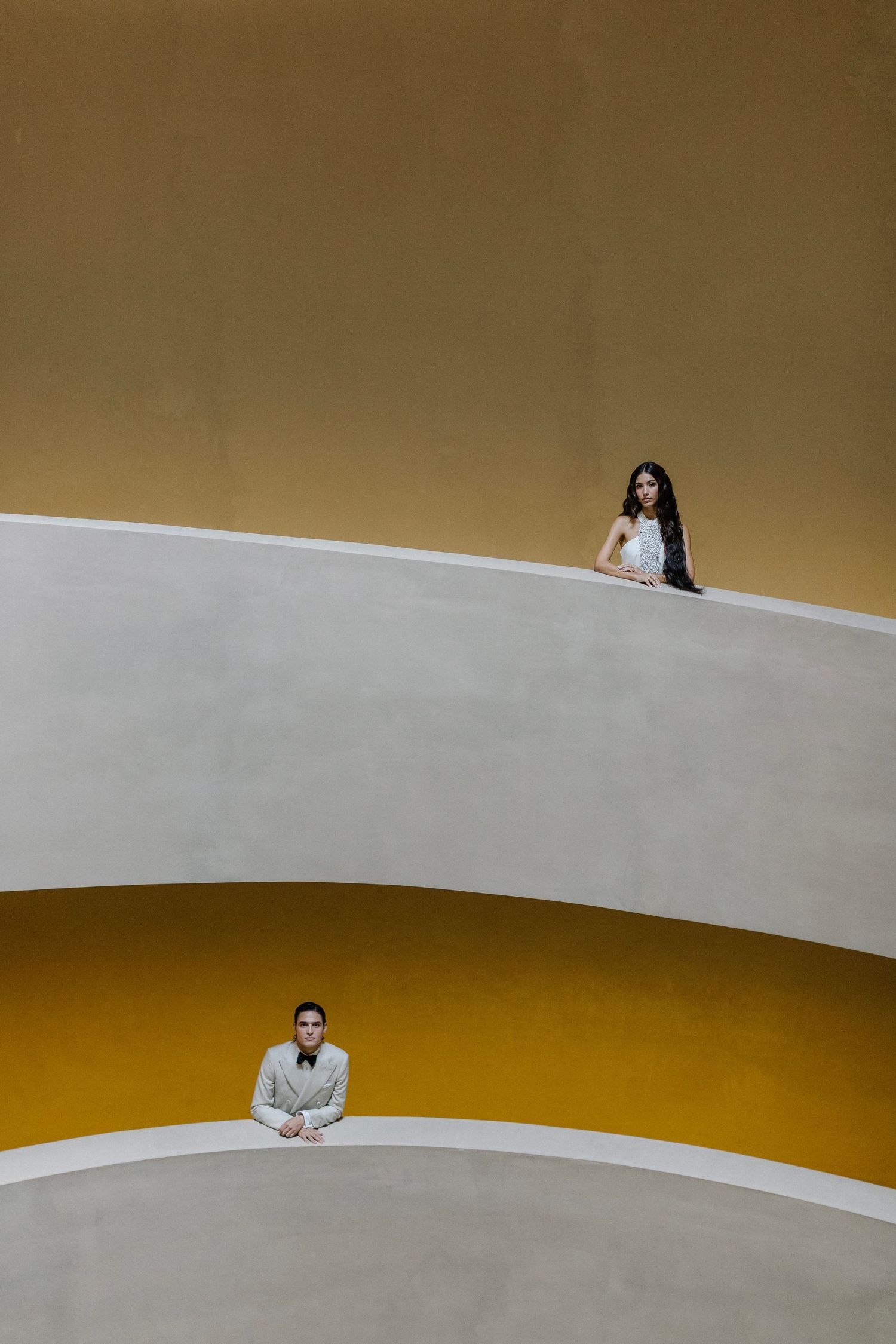 Minimalist architectural composition showing a curved white wall against a golden brown background.