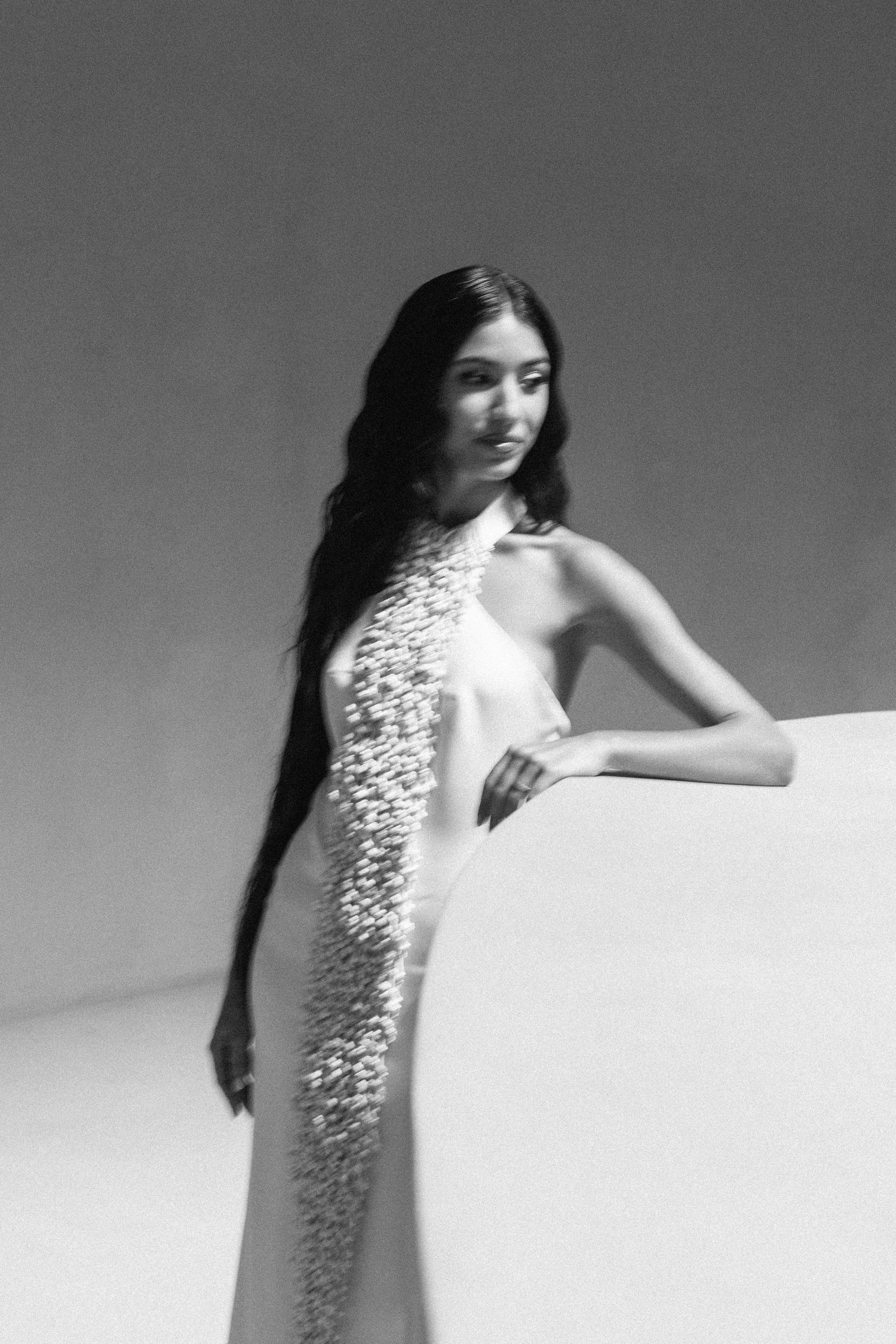 A sequence of artistic black and white photos showing a white dress with embellished details in motion.