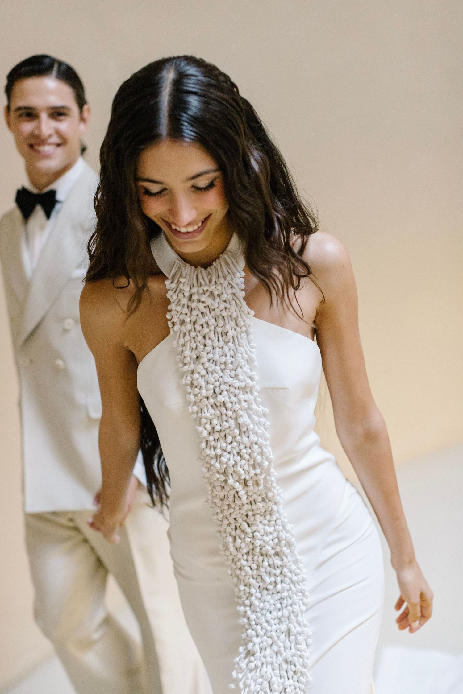 A series of candid moments showing a white wedding dress with beaded details in warm lighting.