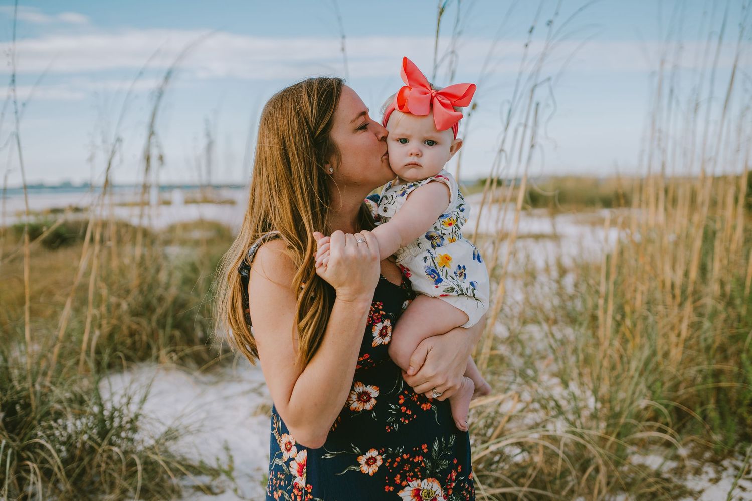A series of five outdoor family photos taken in a coastal setting with tall grass and natural lighting.