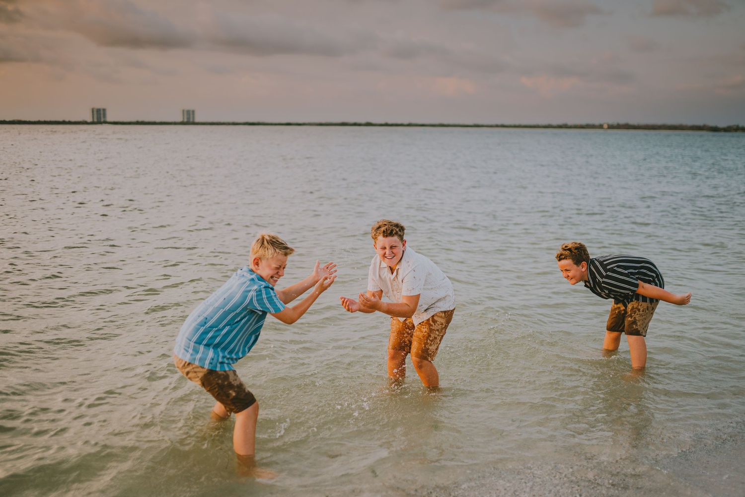 A series of photos showing people playing and splashing in shallow ocean water at sunset.