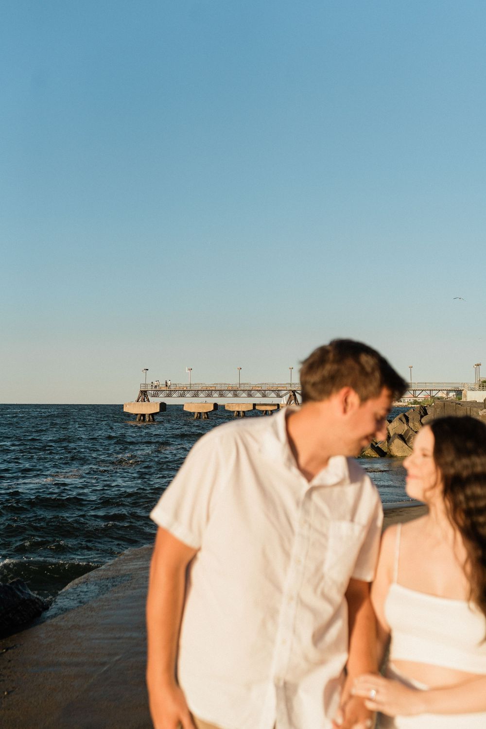 Couple sharing intimate moment by pier during sunset.