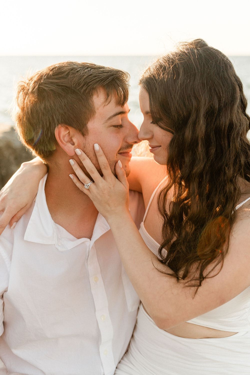 Tender moment between couple against sunset backdrop with warm lighting.