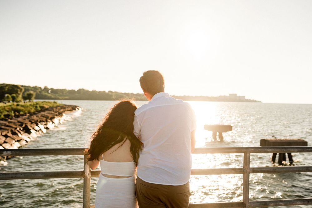 Couple enjoying sunset together on wooden pier by the ocean.