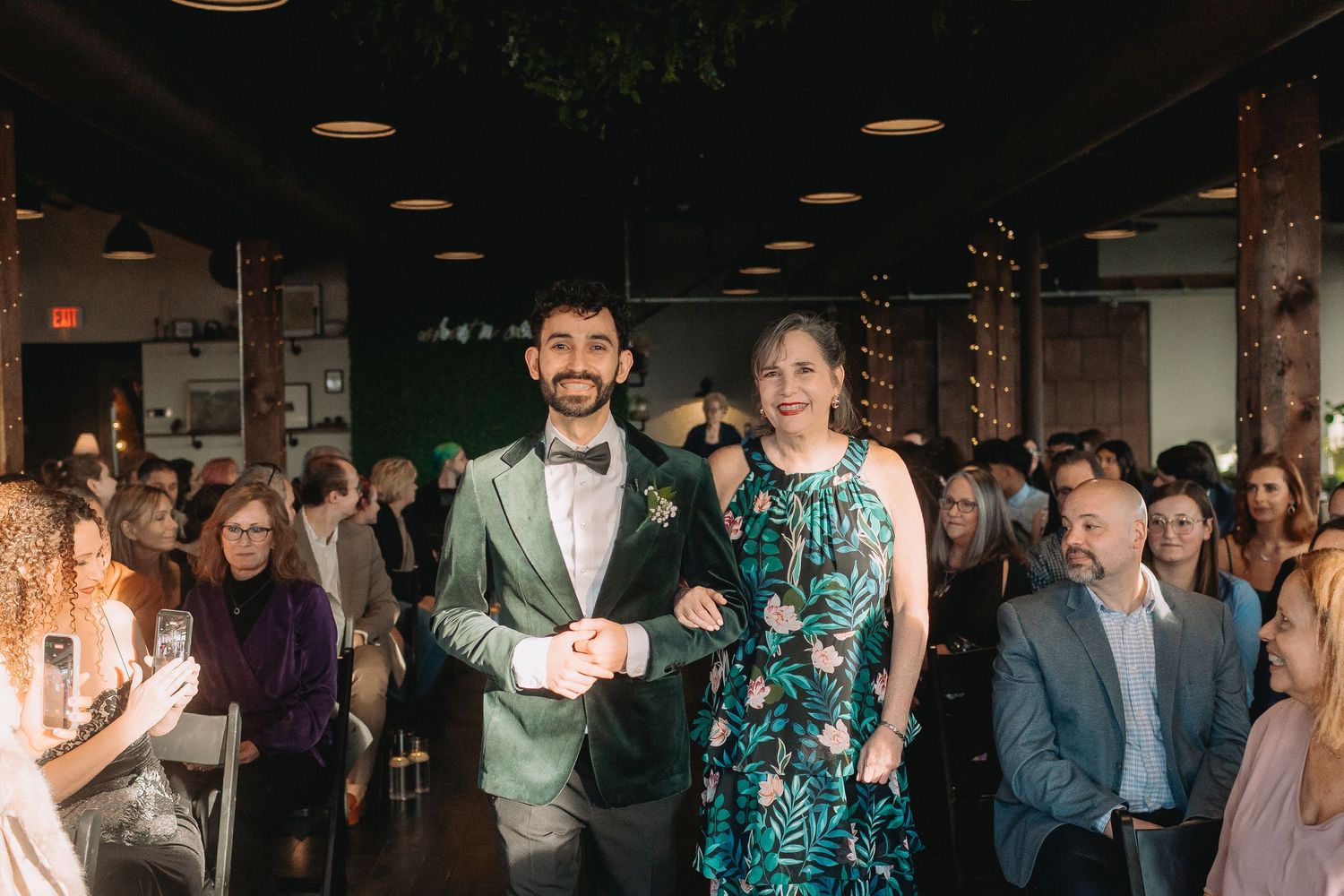 Wedding guests dance and celebrate on a dimly lit dance floor during an evening reception celebration.