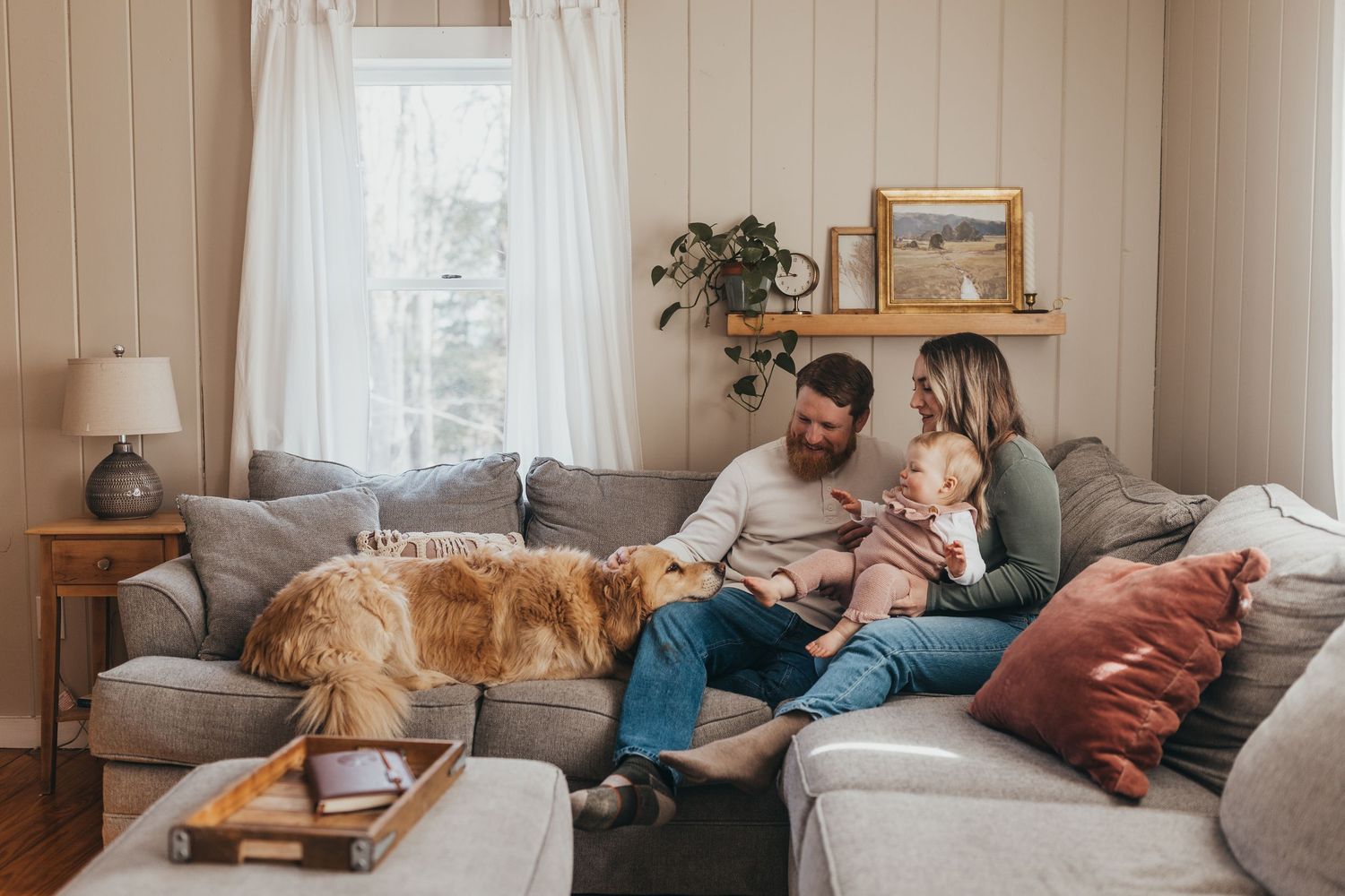 Cozy living room interior with natural light streaming through white curtained windows.