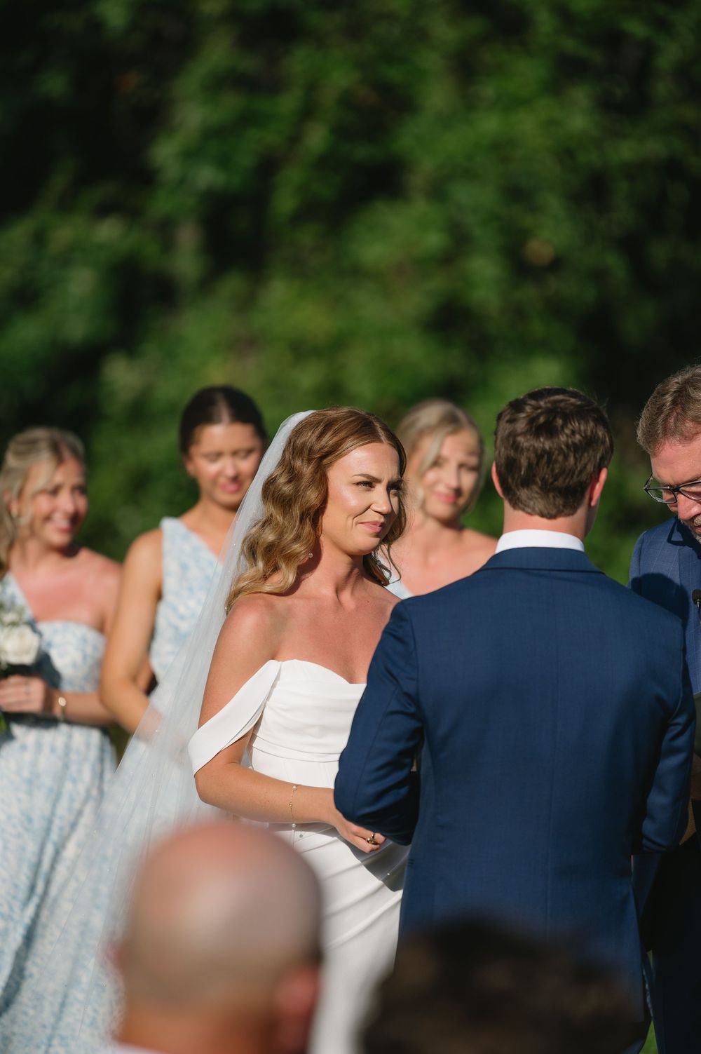 Wedding party poses for photos outdoors with bridesmaids in light blue dresses.