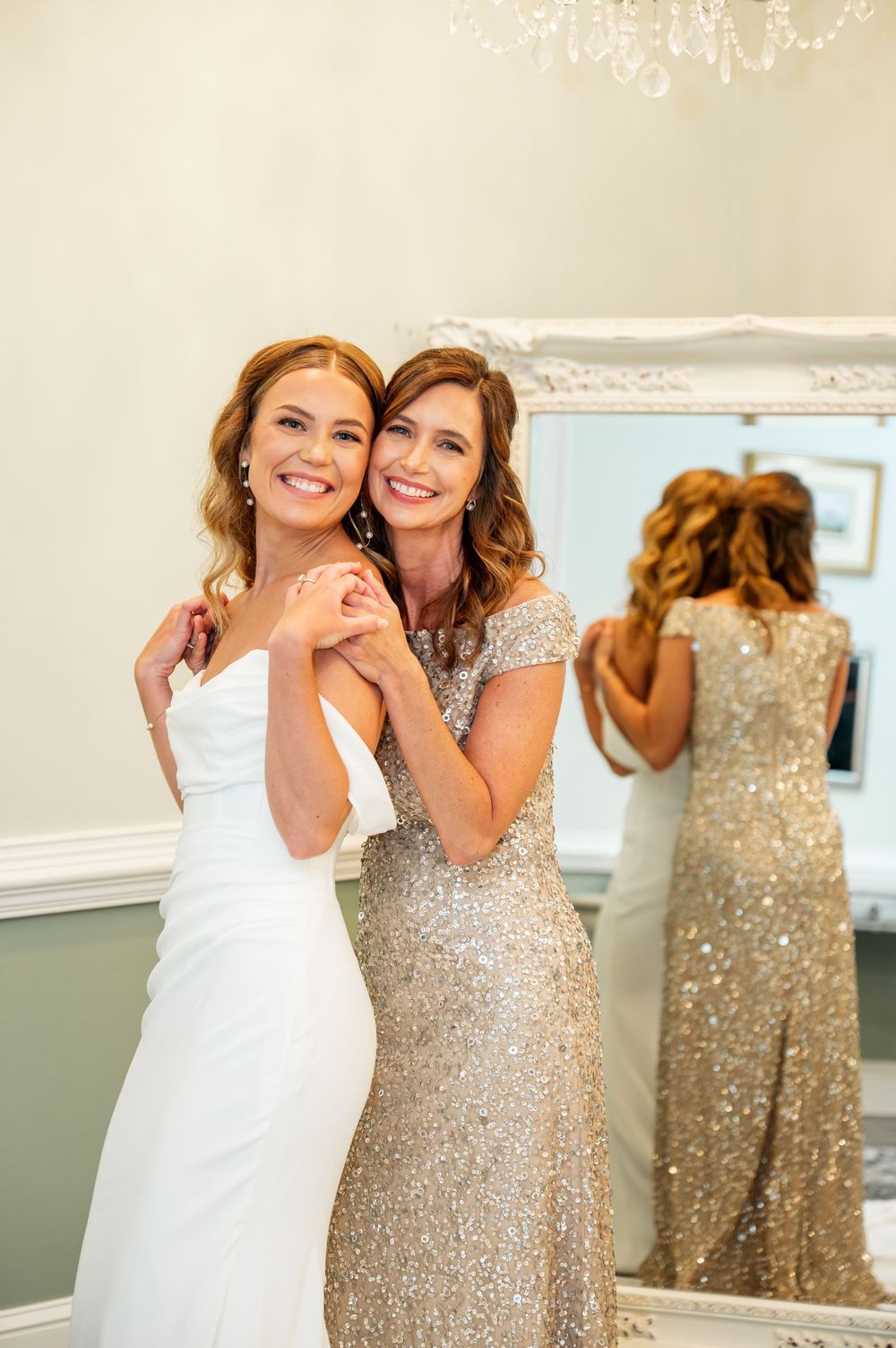Wedding party members share emotional moments in white and sparkly dresses.