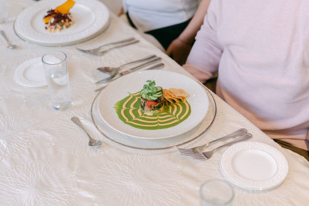 Elegant plated dish featuring a vibrant green sauce artfully swirled on white china with delicate garnish.
