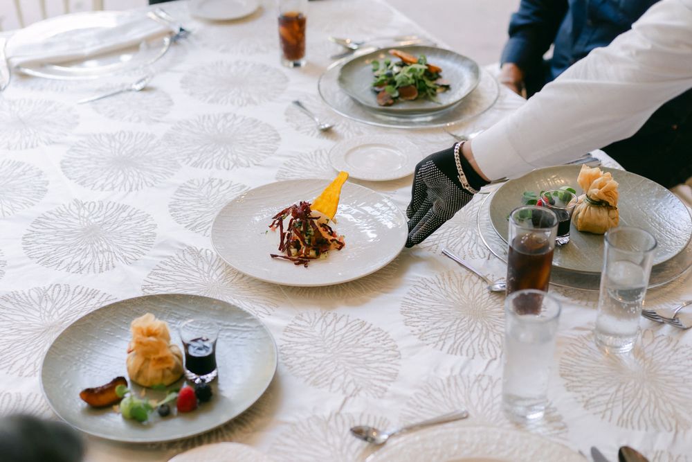 Elegant plated dishes and wine glasses on a white tablecloth in an upscale restaurant setting.