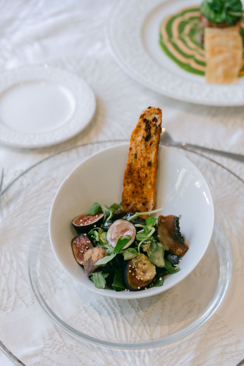 Fresh salad with grilled meat and microgreens plated on elegant white dishes.
