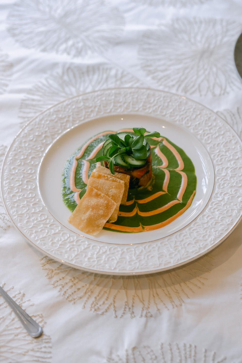Elegantly plated seafood dish with microgreens and orange sauce on a white textured plate.