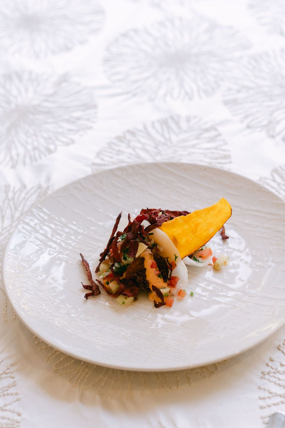 Modern dish featuring roasted vegetables and citrus segments arranged artfully on white dinnerware.