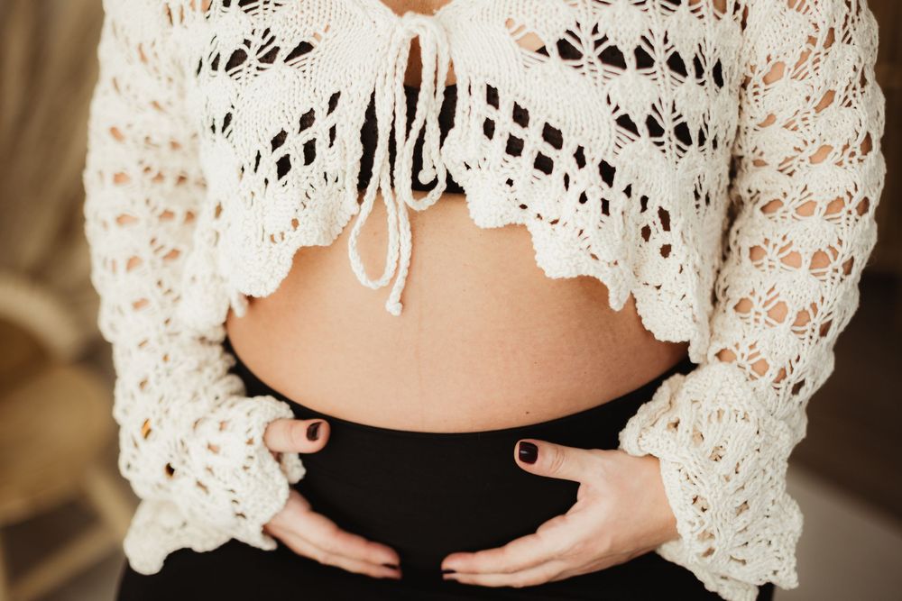 A close-up view of delicate white lace crochet details on a garment against a neutral background.