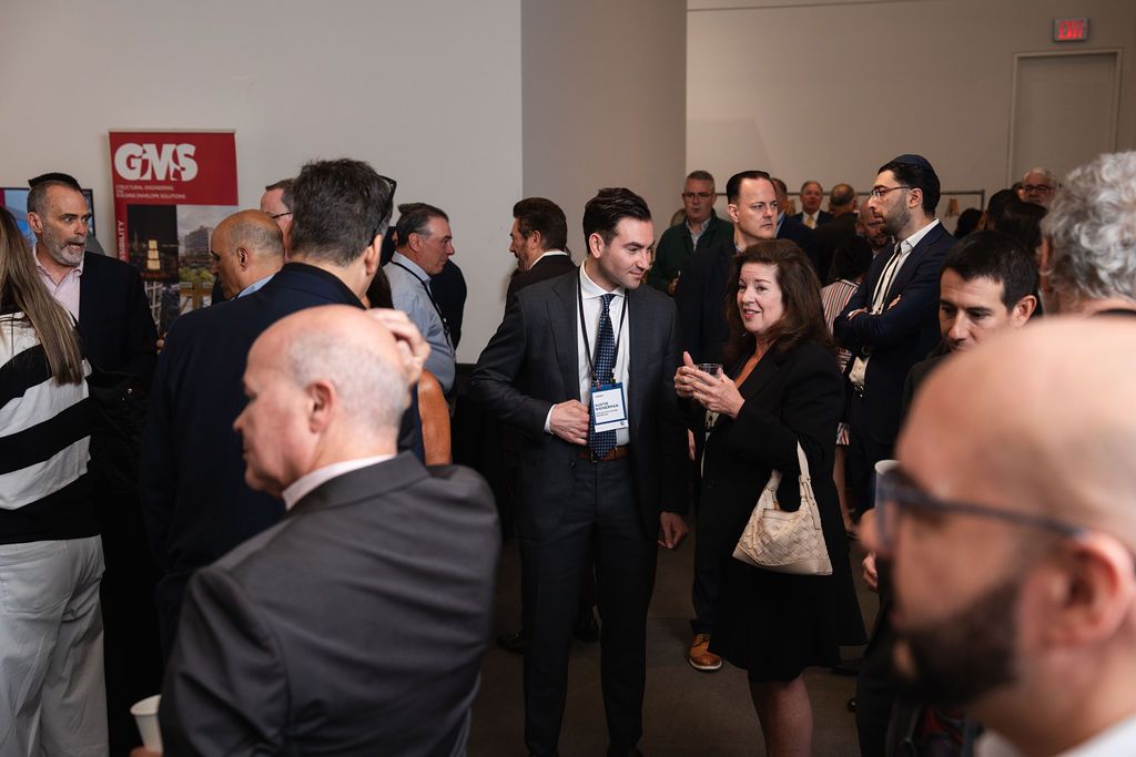 Professionals networking at a busy conference event with attendees in business attire conversing in a modern venue.